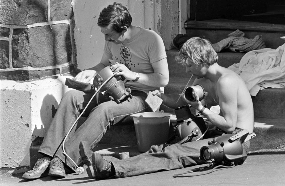 Actors Geoffrey Heath (left) and Simon Marley-Jones clean spotlights damaged by smoke in the 1979...