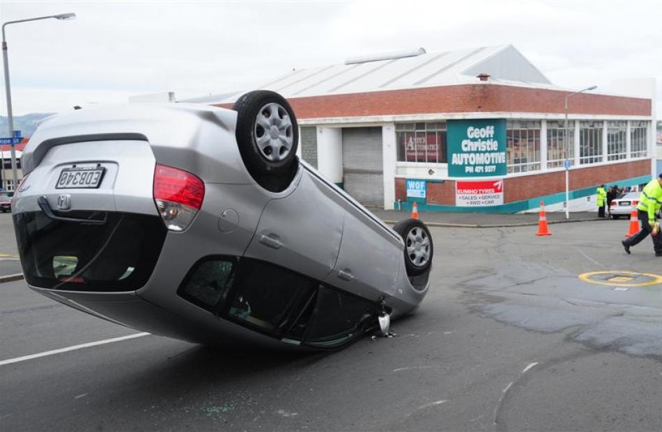 A Honda Fit lies upturned after a collision with a Lancer sedan at the intersection of Carroll...