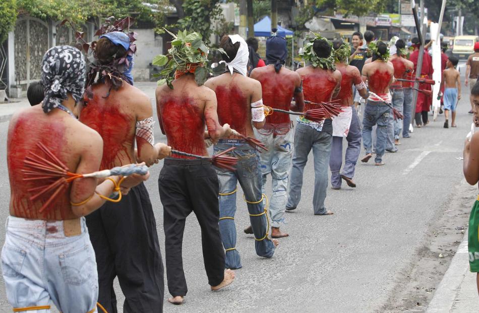 Hooded barefoot penitents perform self-flagellation to atone for their sins in San Fernando,...