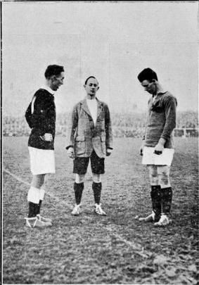 New Zealand captain Dan Jones (left) and Canadian captain Jack ''Red'' Monaghan wait for referee...