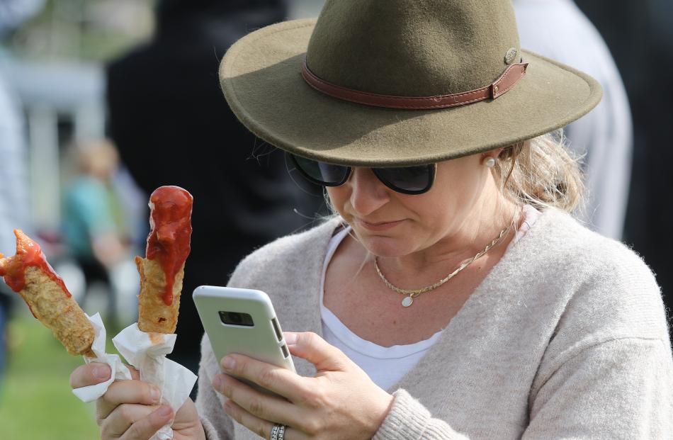 Hollie Mason of Oxford, balances taking a call and  a pair of hot dogs at the show. PHOTO: JOHN...