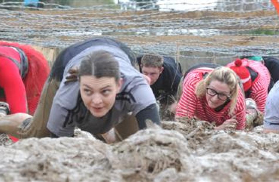 Competitors  crawl beneath the barbed wire.