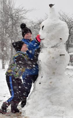 Tomas (TJ) Huntley (9) gives his sister Lani (11) advice as she gives their snowman in Brockville...