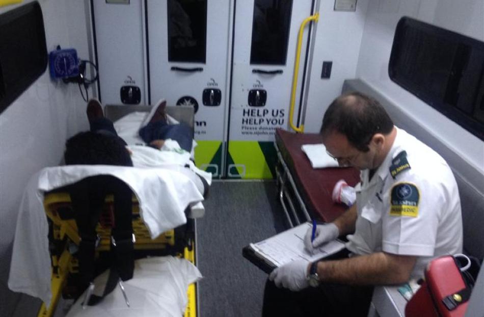 Ambulance officer John Baker attends to some paperwork as a student lies in the ambulance.