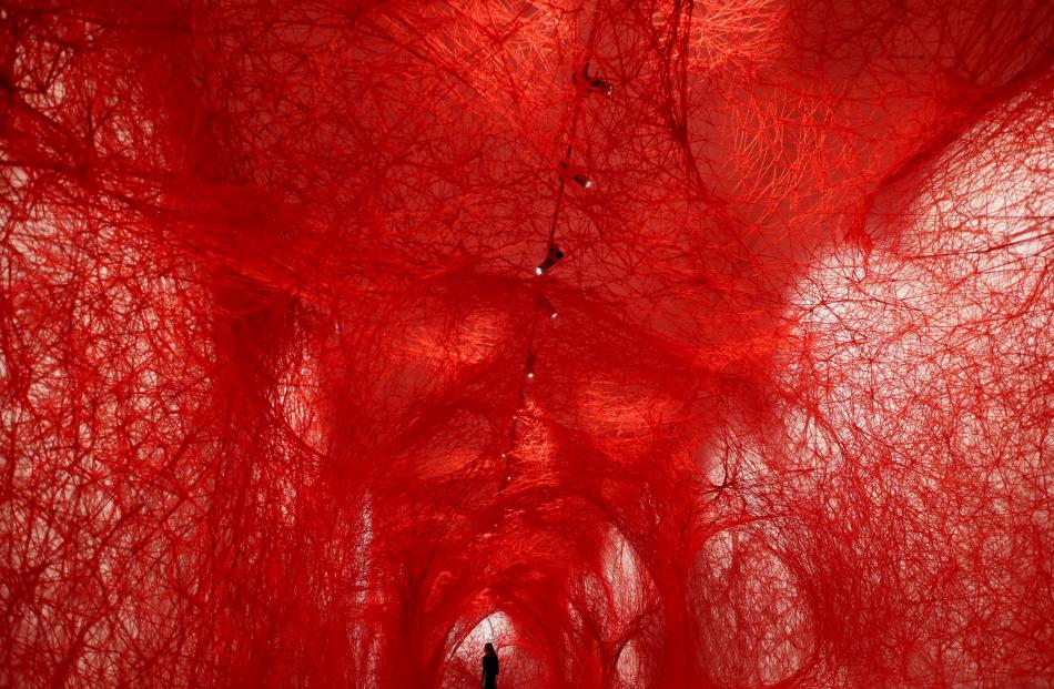 A woman stands inside the art piece The network, by the Japanese artist Chiharu Shiota, exhibited...
