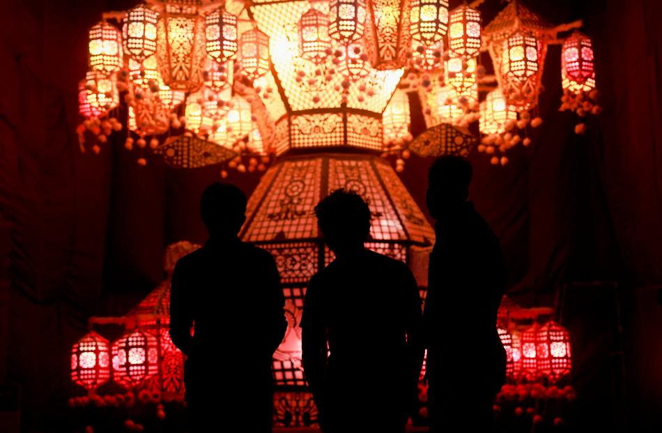 People look at a pandal, a temporary platform to be decorated with illuminated panels...