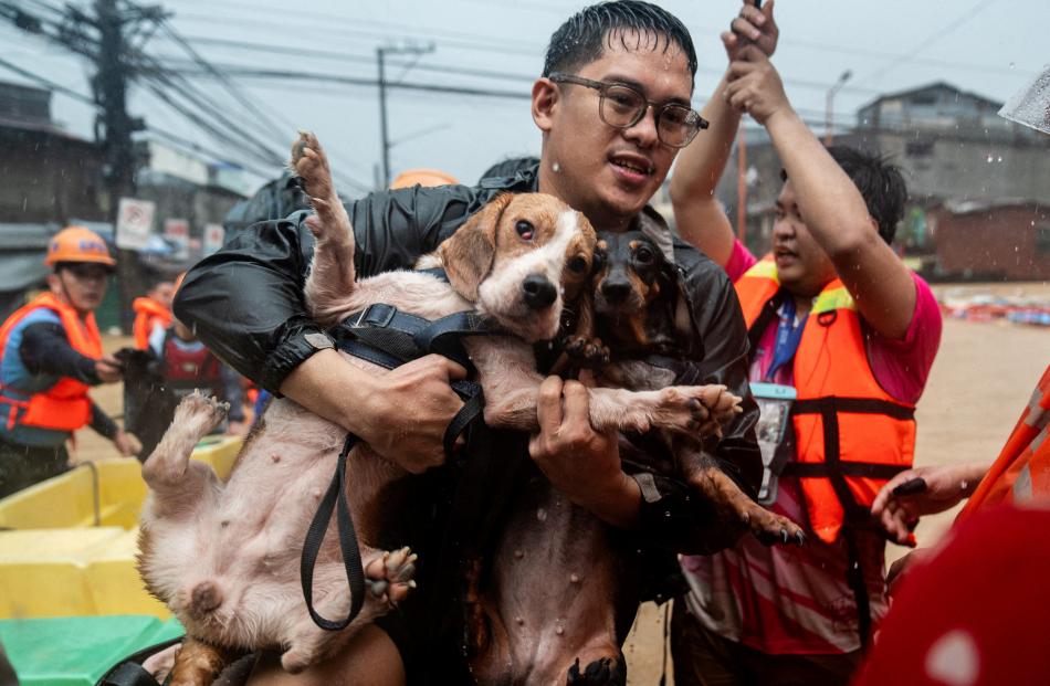 A man carrying his dogs gets off a boat along a flooded road in Marikina City, Philippines....