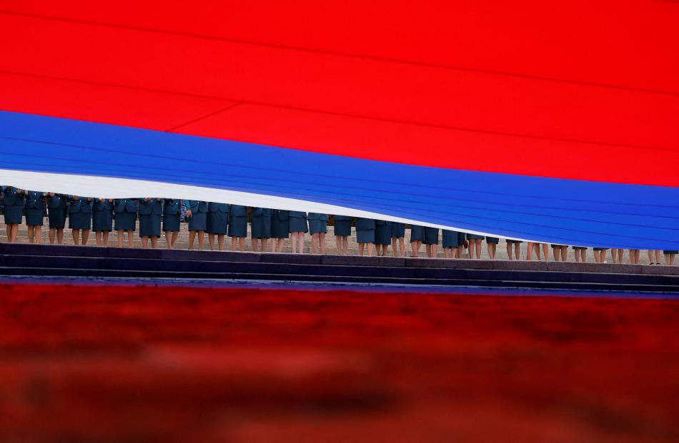 Participants hold a large-size Russian state flag during celebrations of National Flag Day, in...