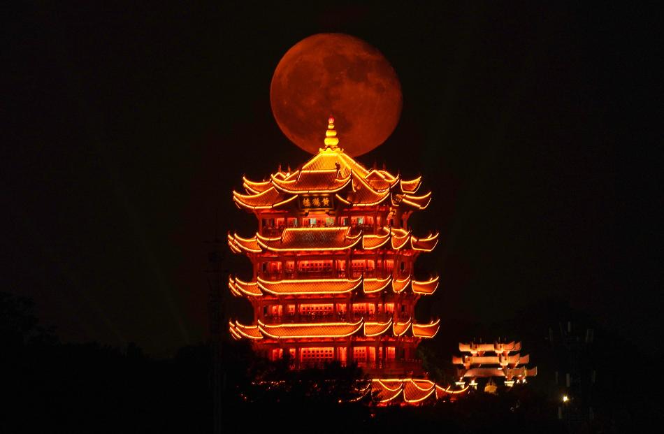 An orange full moon rises behind the Yellow Crane Tower, or Huanghelou, in Wuhan, China. PHOTO:...