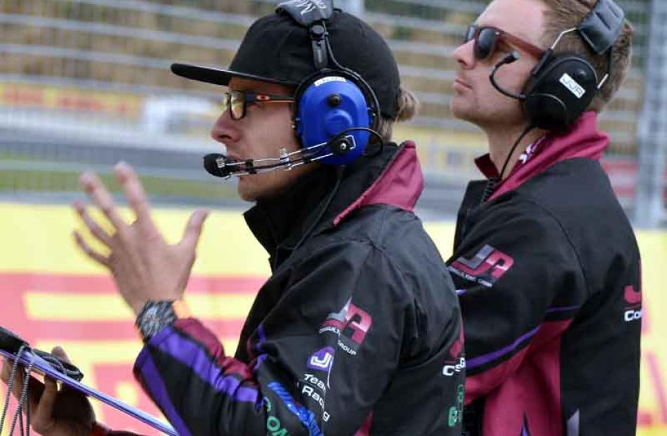 A race car crew talks to the driver of the No. 77 Australian GT car during a practise for the...