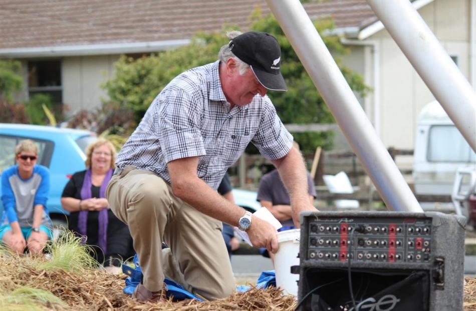 Mike McPhee prepares to bury a time capsule at the Owaka 150th Jubilee Celebrations. It is...