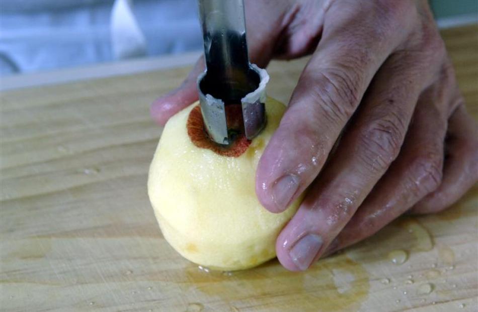 3. To core an apple, place it stem side up on a board. Hold it firmly in one hand and push an...