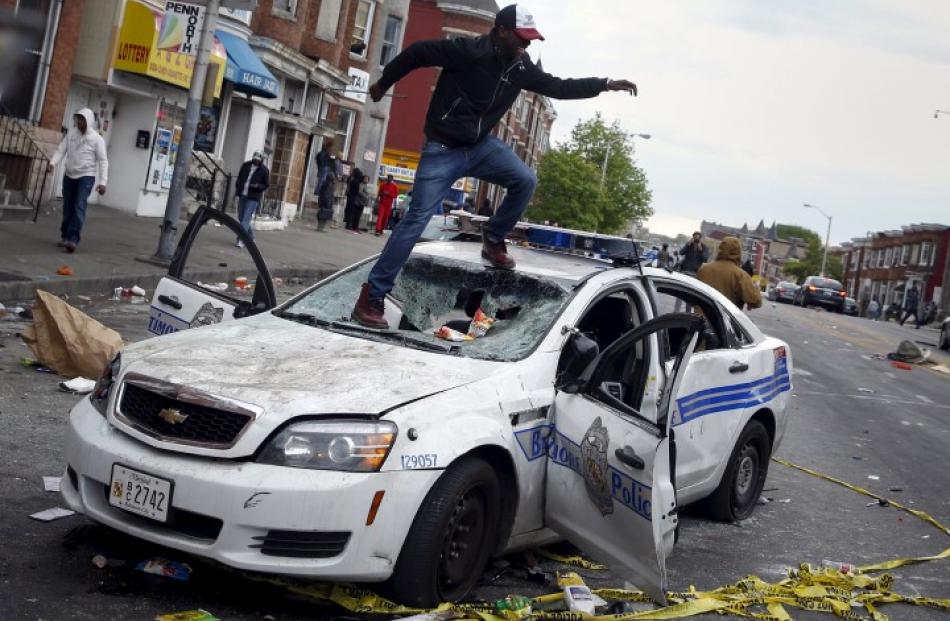 Demonstrators jump on a damaged police department vehicle during clashes in Baltimore. REUTERS...