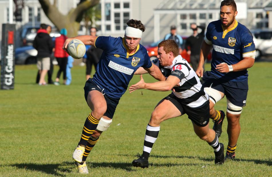 Dunedin flanker Alex Fitzgerald fends off Southern wing Jono Hayes during a drive at the Southern...