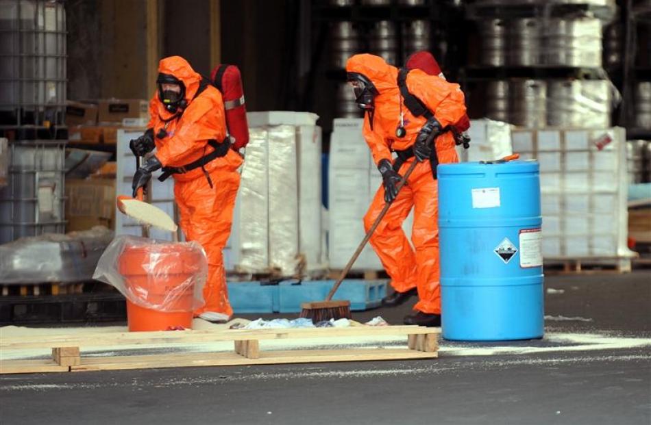 Michael Loo sweeps and Alan McNeill shovels as the firefighters attend to a chemical spill at a...