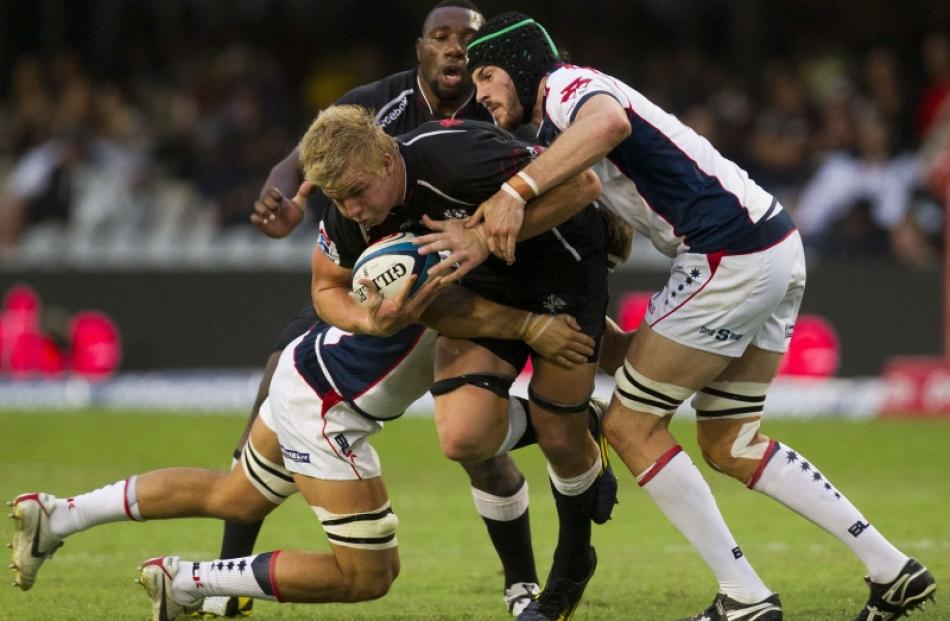 Pieter-Steph du Toit (centre) of South Africa's Sharks is tackled by Hugh Pyle (right) of...
