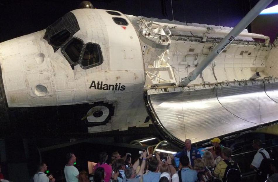 The space shuttle Atlantis towers over visitors on a tour with former Nasa astronaut Tom Jones at...