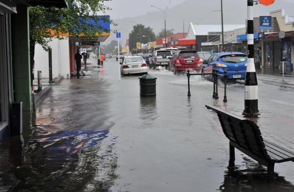 Traffic displaces water, making wake waves on flooded Gordon Rd on Saturday. Photos by Peter...