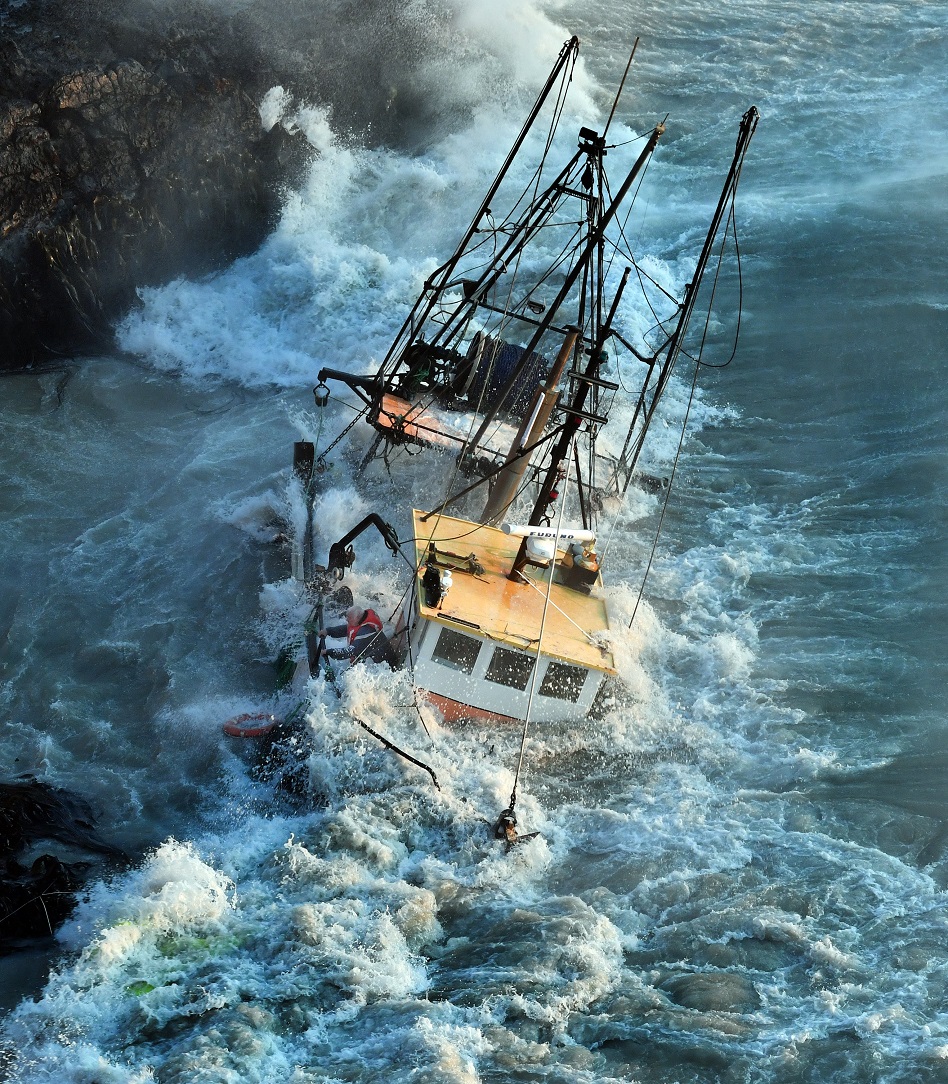 The skipper of Tamahine hangs on to the rail as his boat is pounded by waves after hitting rocks...